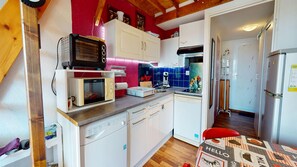 Eine kompakte Küche mit Mikrowelle, Toaster und Kaffeemaschine, Holzschränken und einer roten Wand.