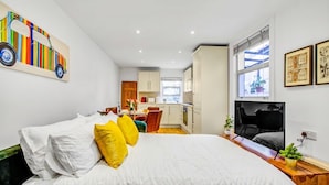 Une chambre à coucher avec un lit, une télévision et une cuisine en arrière-plan.