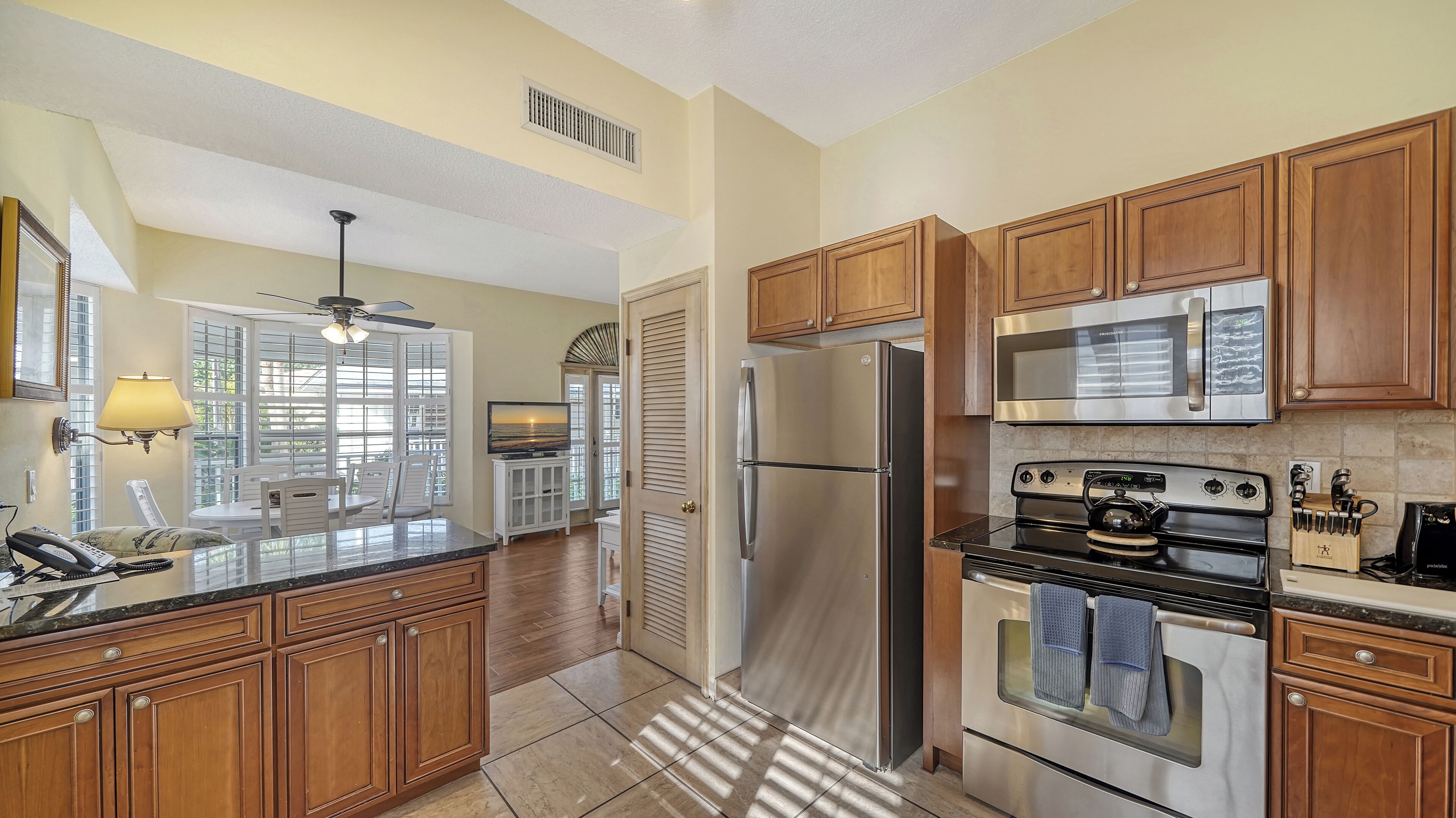 A kitchen with wooden cabinets, stainless steel appliances, a built-in oven, and a dining area with a view.