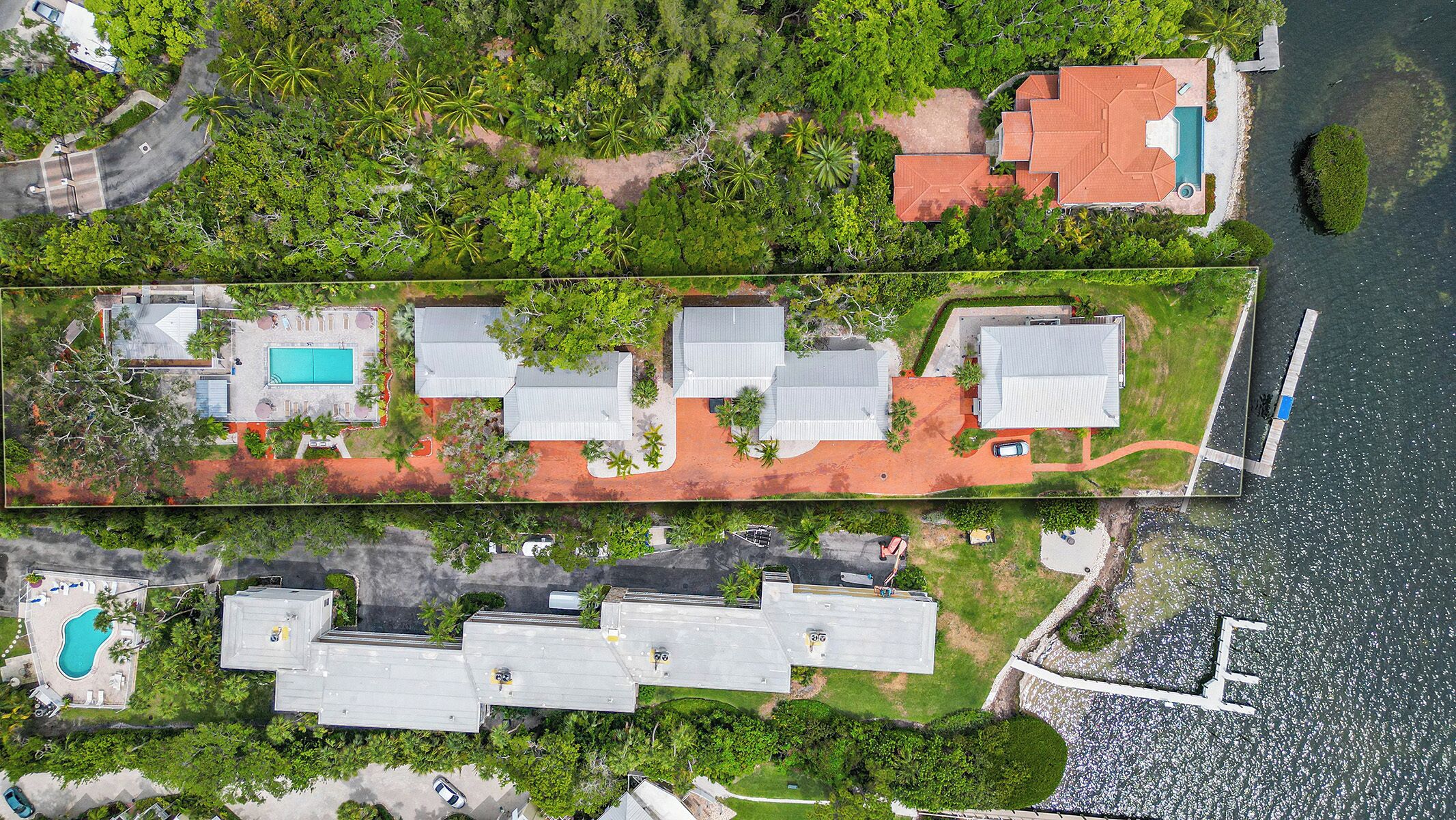 An aerial view of a residential area with multiple houses, a swimming pool, and a dock.