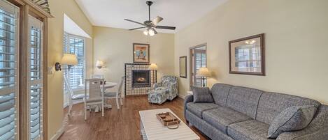 A living room with a fireplace, a sofa, a coffee table, and a dining area with chairs and a table.