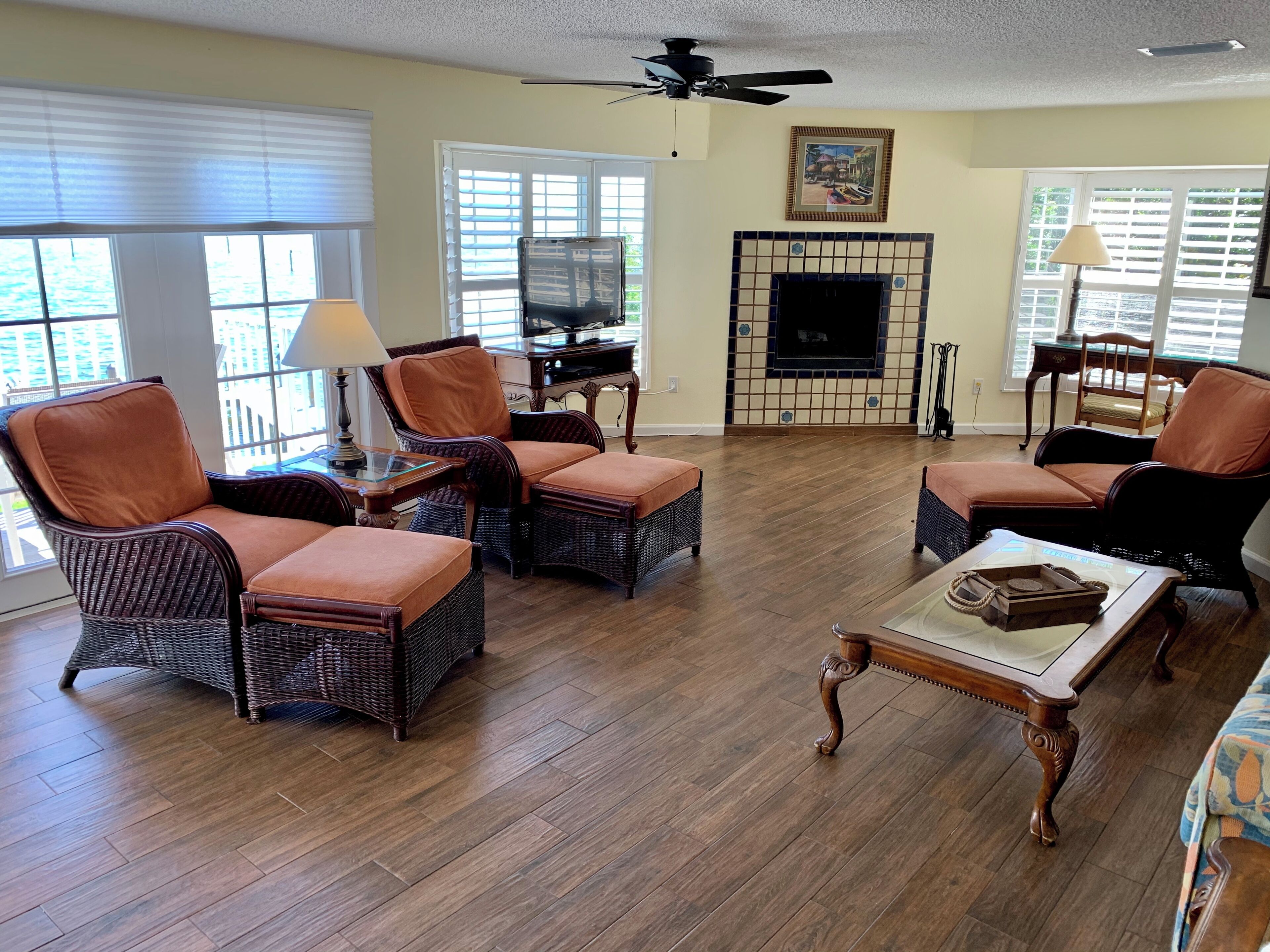 A living room with wicker furniture, a fireplace, and a ceiling fan.