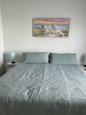 A bedroom with a bed, two pillows, a nightstand with a lamp, and a painting of a beach scene on the wall. - A View to Remember 


Spacious 3-bedroom house in a serene location with AC (Galveston)