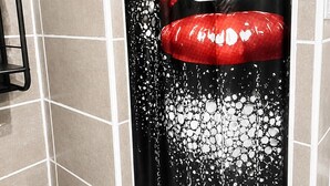 Baño con cortina de ducha que presenta un diseño de labios rojos.