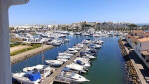 Un puerto deportivo con numerosos barcos amarrados a lo largo de un canal estrecho, rodeado de edificios y palmeras.
