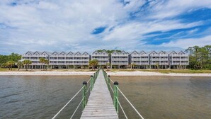 A wooden pier leading to a hotel with multiple balconies and a clear view of the water. - Enjoyable 2-bedroom waterfront condo in charming Carrabelle (Carrabelle)