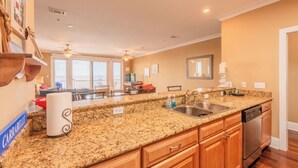 A kitchen with granite countertops, wooden cabinets, a stainless steel sink, and a dishwasher. - Enjoyable 2-bedroom waterfront condo in charming Carrabelle (Carrabelle)