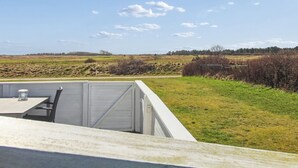 A white outdoor seating area with a table and chairs, overlooking a grassy field and a clear sky. - "Amlethus" - 2.3km from the sea by Interhome (Rømø)