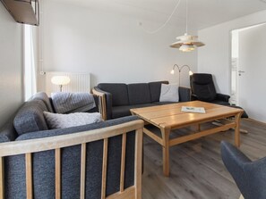 Una sala moderna con un sofá, una mesa de centro de madera y un sillón negro.