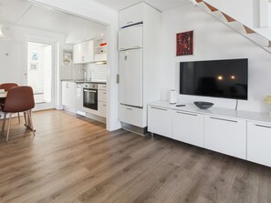 Una cucina moderna con mobili bianchi, forno integrato e un grande televisore su un mobile bianco.