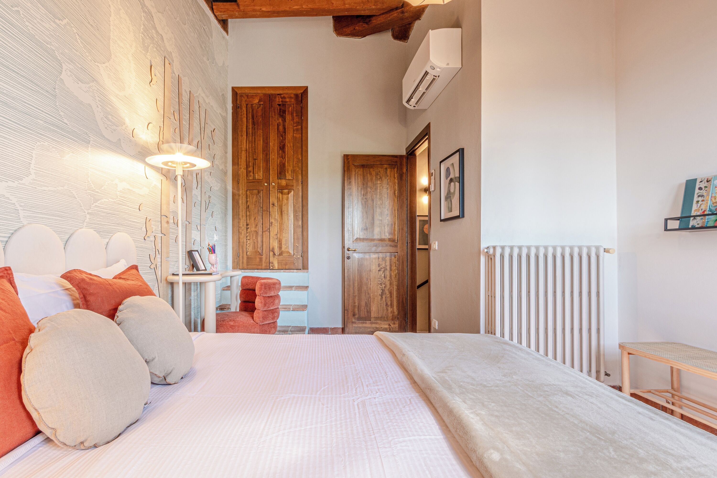 Um quarto com uma cama grande, uma porta de madeira, um radiador e uma mesa pequena.