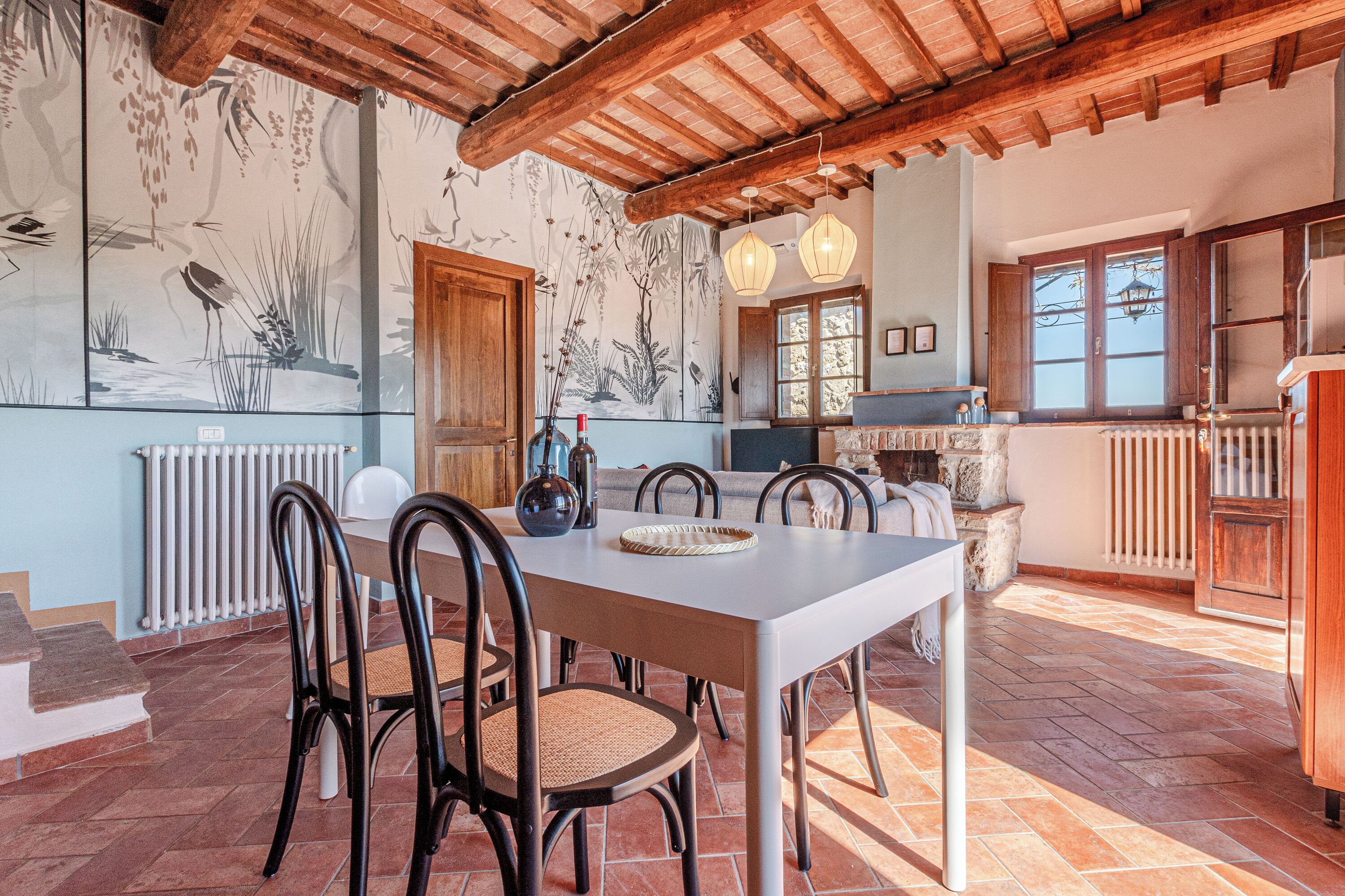 Uma sala de jantar com uma mesa branca, cadeiras pretas e teto rústico.