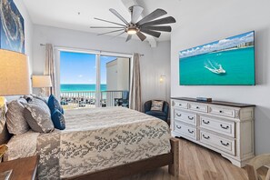 Ein Schlafzimmer mit Bett, Kommode, Fernseher und Meerblick.