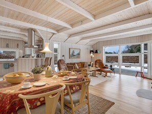 A spacious dining area with a large table, chairs, and a view through the glass doors.