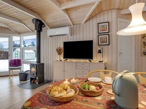 A cozy room with a fireplace, a television, and a dining table set with bread and fruit.