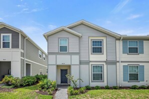 A two-story residential building with a front entrance, a small garden area, and a paved pathway leading to the door. - 5BR house sleeps 12 with game room and pool (Davenport)