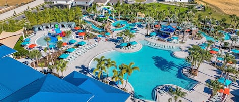 An aerial view of a resort with a central swimming pool, multiple water slides, and sun loungers.