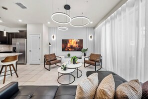 This stylish living room features sleek black leather sofas paired with warm wooden accents. The soft glow from modern light fixtures complements the airy feel created by the large windows, inviting you to unwind in comfort. - 5BR townhouse with private pool in davenport (Davenport)