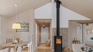 A modern interior with a central fireplace, wooden flooring, and a dining area with chairs and a table.
