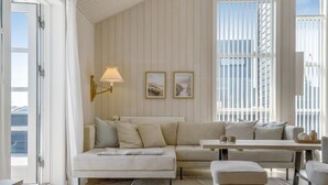 A room with a white sofa, a small table, a lamp, and framed pictures on the wall.