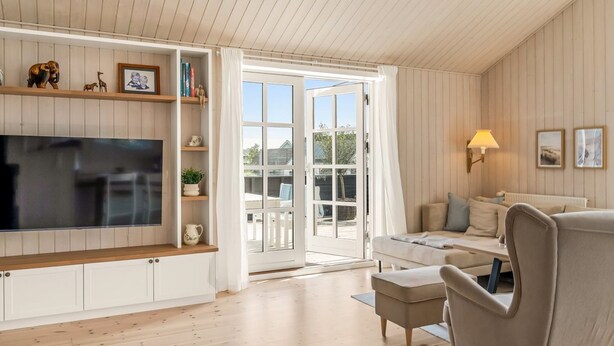 A living room with a TV, sofa, and a dining area.