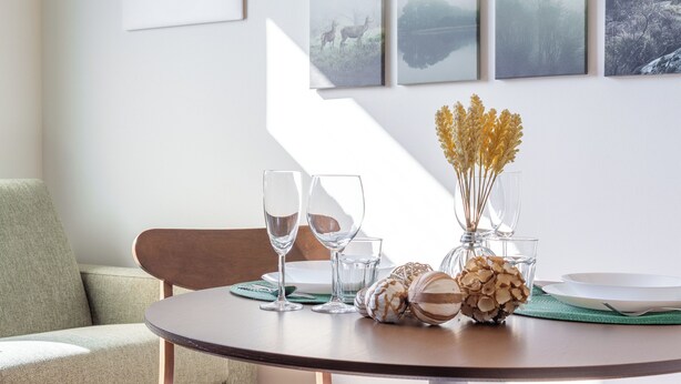 A round dining table with clear glasses, a vase with dried flowers, and a plate. - Flower Residence - Appartamento Hibiscus (Lissone)