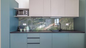 A compact kitchen with a microwave, kettle, and sink. - Flower Residence - Appartamento Hibiscus (Lissone)