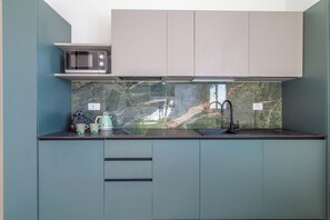 A compact kitchen with a microwave, kettle, and sink. - Flower Residence - Appartamento Hibiscus (Lissone)