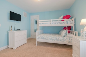 A bunk bed room with a television, dresser, and a door leading to another room. - JL #714 - Sunset Splendor -  Luxurious Soundfront Home - Hot tub - Elevator (Kill Devil Hills)