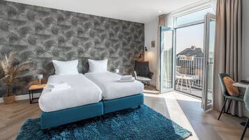 Una habitación de hotel moderna con una cama grande, un balcón con vistas y una pared con diseño de piedra.