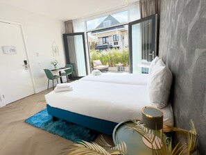Une chambre d’hôtel moderne avec un grand lit, un bureau et une vue sur l’extérieur.