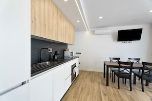 A modern kitchen with white cabinets, a black countertop, and a dining area with wooden chairs and a table. - Vacation Apartment 'Ale Deluxe Home' with Sea View, Wi-Fi and Air Conditioning (Santiago del Teide)