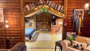 Ein gemütliches Blockhaus-Interieur mit Schlafgalerie, Holzwänden, einer Essecke und einer kleinen Küchenzeile.