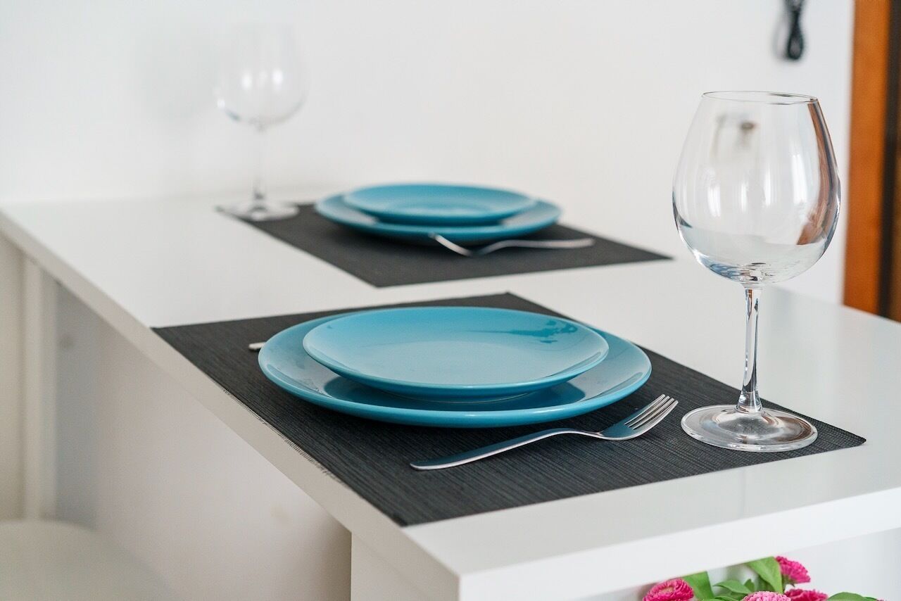 A dining table with blue plates, a wine glass, and a fork.