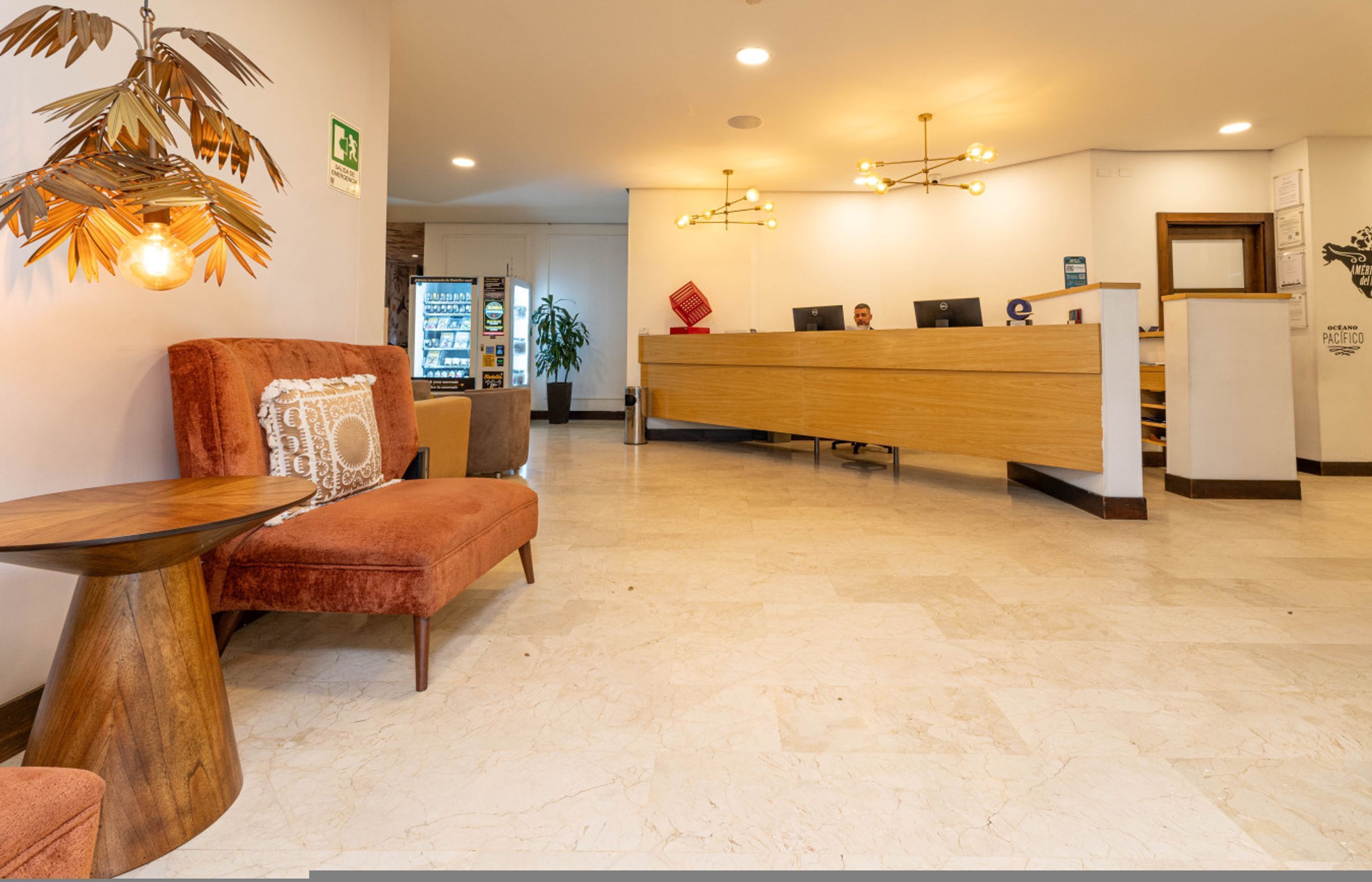 A reception area with a wooden desk, a reception counter, and a seating area with a chair and a table.