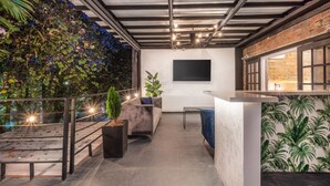 A rooftop terrace with a seating area, a bar, and a wall-mounted TV. - Casa Madera Parque Lleras With Private Jacuzzi (Medellín)