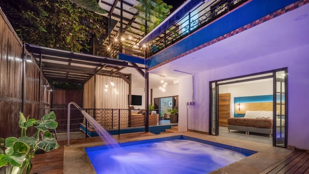 A modern outdoor pool area with a hot tub, wooden deck, and a balcony overlooking the pool. - Casa Madera Parque Lleras With Private Jacuzzi (Medellín)