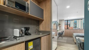 A modern kitchen with a microwave, toaster, coffee maker, and a small refrigerator. - Go Living Suites - 1305 (Medellín)