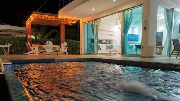 A modern pool area with a hot tub, outdoor seating, and a glass-enclosed living space. - Luxury Villa Private Beach Tolu (Tolú)