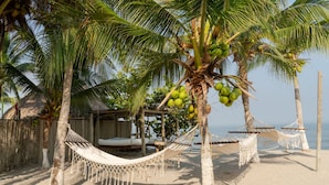 A beach with hammocks, palm trees, and a wooden structure. - Luxury Villa Private Beach Tolu (Tolú)
