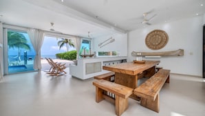 A spacious living area with a wooden dining table, benches, a kitchen island, and a view of the ocean. - Luxury Villa Private Beach Tolu (Tolú)