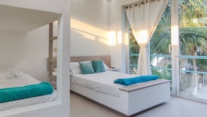 A bedroom with a bed, a bench, and a window with curtains. - Luxury Villa Private Beach Tolu (Tolú)