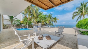 A beachside patio with white lounge chairs, a small pool, and palm trees. - Luxury Villa Private Beach Tolu (Tolú)