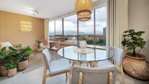 A modern living room with a glass table, wicker furniture, and a city view. - Alcazar Oviedo - 1103 (Medellín)