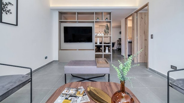 A modern living room with a flat-screen TV, a bench, a coffee table with magazines, and a vase with green plants. - Oslo 703 in Medell n (Medellín)