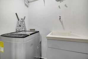 Habitación pequeña con lavadora y lavamanos.
