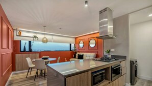 A modern kitchen with a central island, built-in oven, and a view to the outside. - Go Living Suites - 807 (Medellín)
