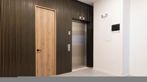 Un ascenseur moderne avec une finition métallique, une porte en bois et un panneau de commande fixé au mur.