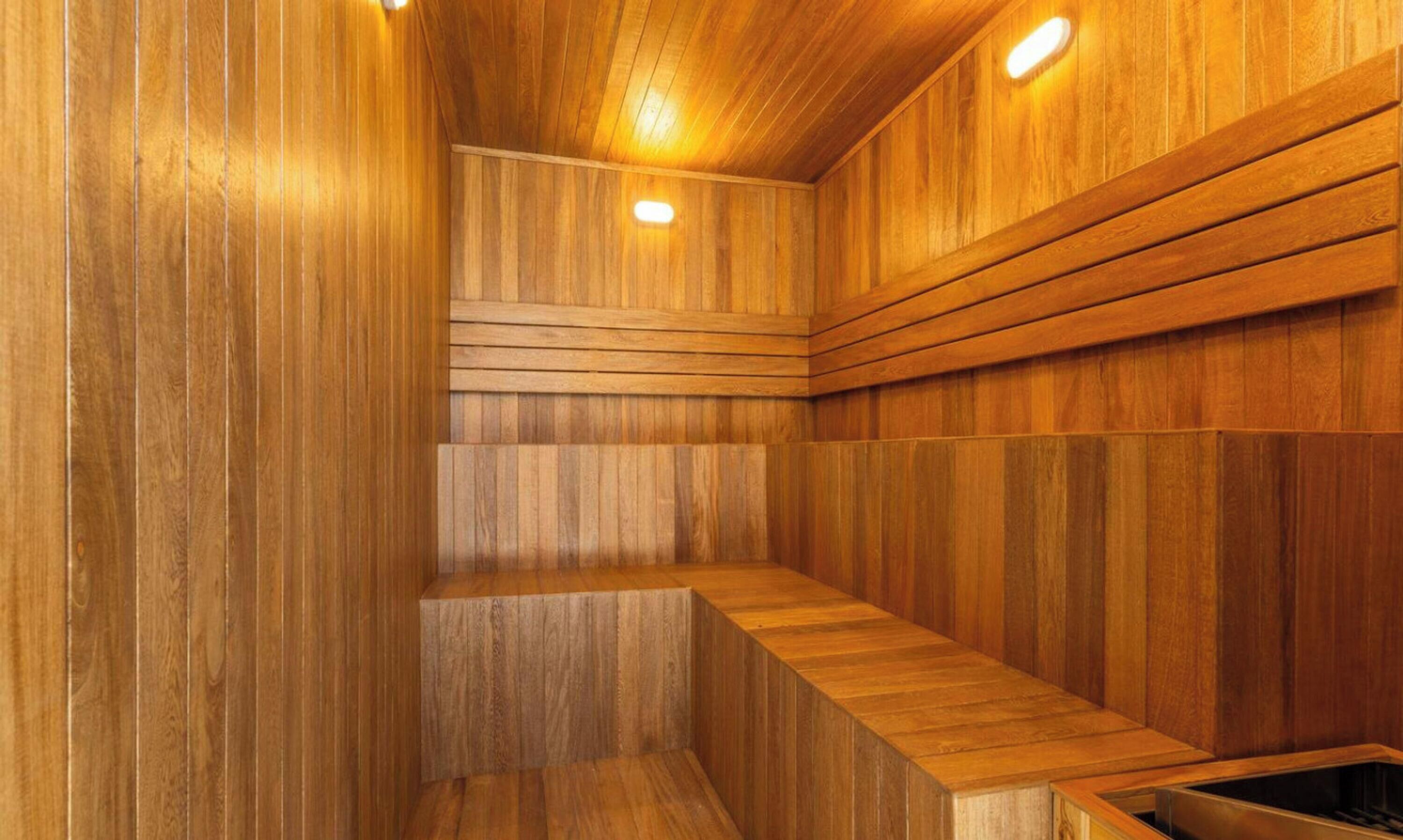 Una sauna amb parets i bancs de fusta, il·luminació empotrada i sostre inclinat.