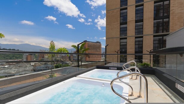 A rooftop pool with metal railings, a clear sky, and a mountain view. - Metropolitan Living - 515a (Medellín)